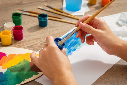 Hobby. Antistress. A girl is painting with a blue gouache brush. Lifestyle. Close-up. Side view.