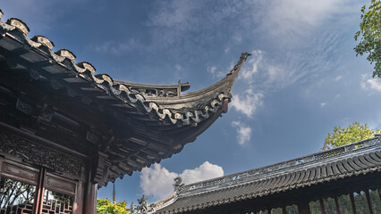 Roofs of Chinese buildings against a background of blue sky and clouds. The curved edges of the cornices are decorated with carvings and ornaments.  China. Shanghai © Вера 