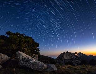 Long exposure shot capturing star trails over a rocky landscape at dusk