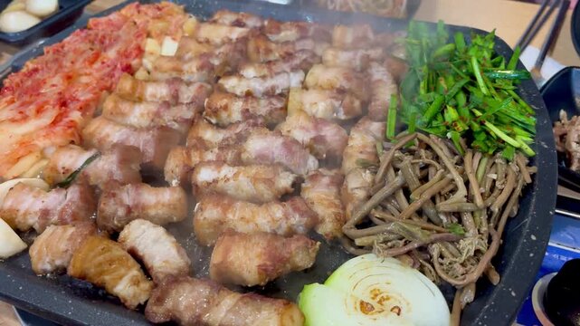 Sizzling Korean pork belly grilled with spicy kimchi on a hot metal plate, mouth-watering BBQ.