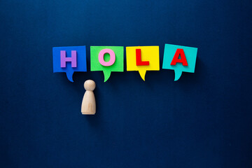 Wooden peg doll with speech bubbles spelling hola © chee siong teh