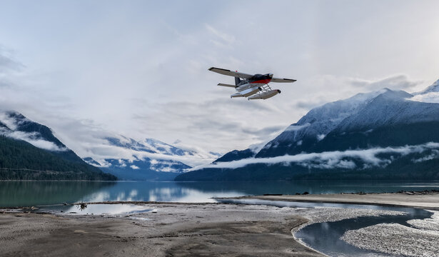 Seaplane Flying Over Snowy BC Mountains And Misty Lake Beneath Wide Sky