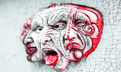 Three heads emerge from the cracks in an old white wall