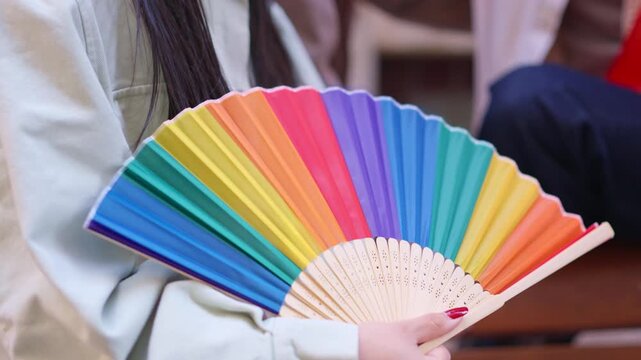 Woman holding a rainbow lgbt pride fan
