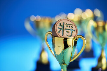 gold colored trophy and chess chess king  against blue background