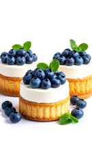Three mini cheesecakes topped with blueberries and mint leaves, isolated on a white surface, in a vertical arrangement