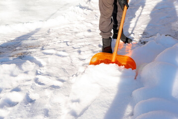 Removing a lot of snow by orange plastic shovel outdoor