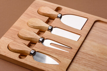 A set of cheese knives with a wooden cutting board, slicing tools. Cheese knives