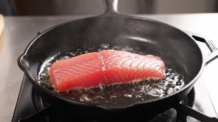 Person placing fish fillet in a hot cast iron skillet.