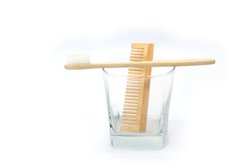 Natural Wooden Toothbrush and Comb in Glass Cup on White Background