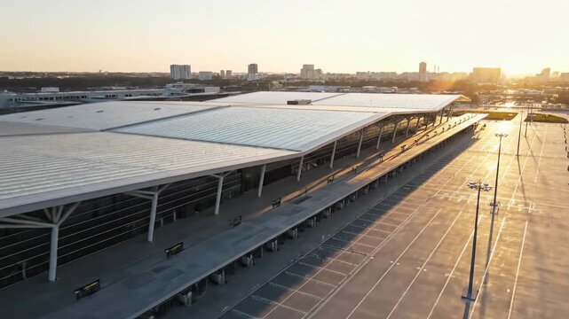 Stunning aerial drone shot sweeping over a large, modern, empty bus depot infrastructure and geometric station architecture bathed in bright morning sunlight commercialuse, movement, system