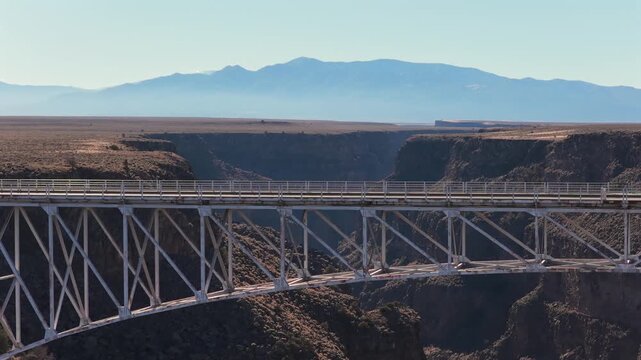 The Rio Grande Gorge Bridge on Highway 64 spans a deep volcanic canyon near Taos New Mexico. The steel truss structure sits high above the Rio Grande River on the arid Taos Plateau landscape.