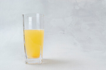 Effervescent orange vitamin C tablet dissolving in a glass of water with bubbles on a bright white background.