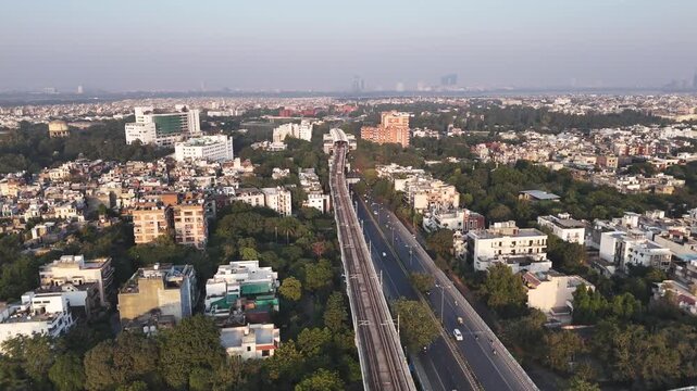 Aerial footage of Modi Mill Flyover Metro train departs from Sukhdev Vihar A tranquil sunset paints South Delhi in warm hues where modern infrastructure meets sprawling under a fading golden sky.