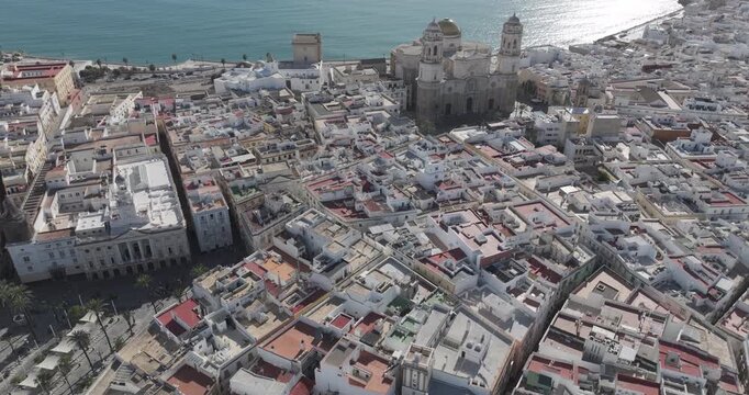 Aerial drone wide view cityscape of Cadiz in Spain, Andalusia, Europe, on bright sunny day, facing C&aacute;diz cathedral and waterfront. Cinematic establishing shot
