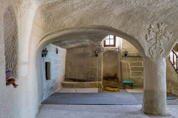 Cavusin Old Rock Mosque interior, Cavusin Koyu Eski Kaya Camii, Cavusin, Cappadocia, Turkey. Ancient rock-cut architecture, mihrab, prayer rugs, and carved details.