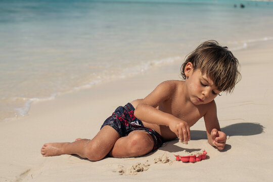 Young boy on beach playing with sand