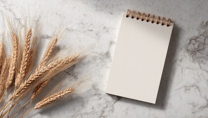 Wheat & blank notepad on marble surface, soft light