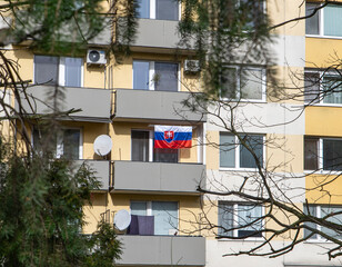 The Slovak national flag hanging from a private apartment balcony on a residential building, showing national pride