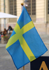 Blue and Yellow color National Flag of Sweden  on stick  with Blurred Background at Gamla Stan in Stockholm, Sweden