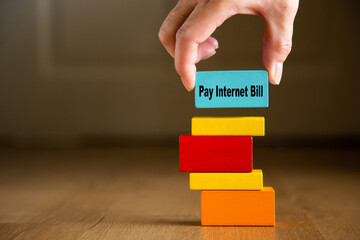 Hand placing pay internet bill block on spending stack