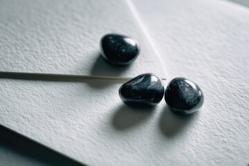 Three Dark Stones On White Envelope