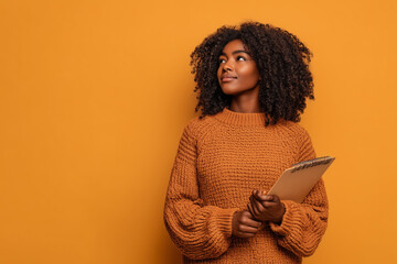 Thoughtful young woman with notebook looking up with a curious expression on her face