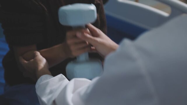 Old woman training with physiotherapist using dumbbells at home. Therapist assisting senior woman with exercises in nursing home. Elderly patient using dumbbells with outstretched arms.