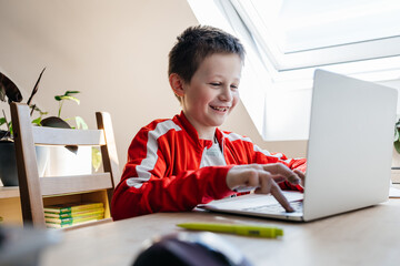 Young boy learning online using laptop at home