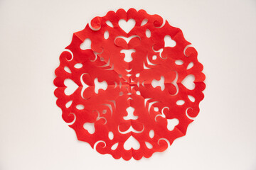 Red paper cutout with heart-shaped patterns on white.