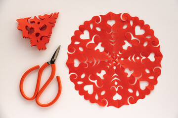 Red paper cuttings and scissors on a white background.