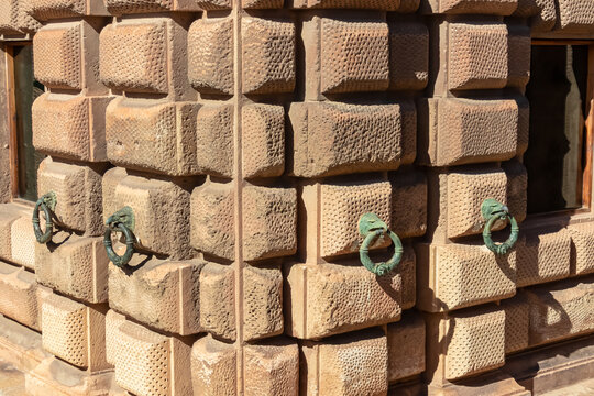 The rusticated stone facade of the Palace of Charles V features bronze eagle rings attached to the massive wall in the Alhambra. This Renaissance detail contrasts with the Moorish site in Granada.