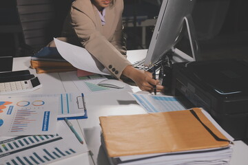 business documents on office table with tablet, smart phone and laptop and two colleagues discussing data