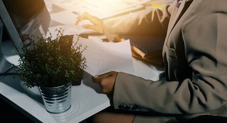 business documents on office table with tablet, smart phone and laptop and two colleagues discussing data