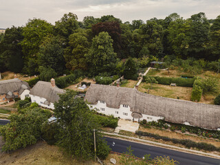 Salisbury UK: 27th July 2025:Thatched-roof houses in Salisbury, surrounded by trees and gardens. The scene shows a road winding through the area