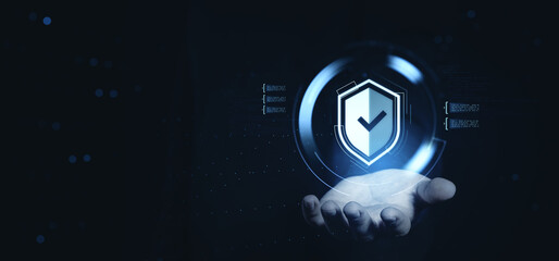 Cybersecurity protection concept with holographic shield icon floating above a human hand on futuristic digital background interface.