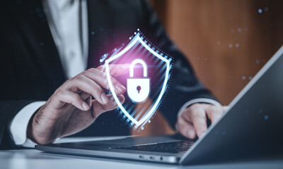 Businessman touching digital padlock hologram on laptop screen, representing cybersecurity and data protection concept on futuristic background.