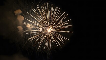 Naklejka premium Bright yellow and white starburst fireworks exploding in a dark night sky with smoke trails explosion