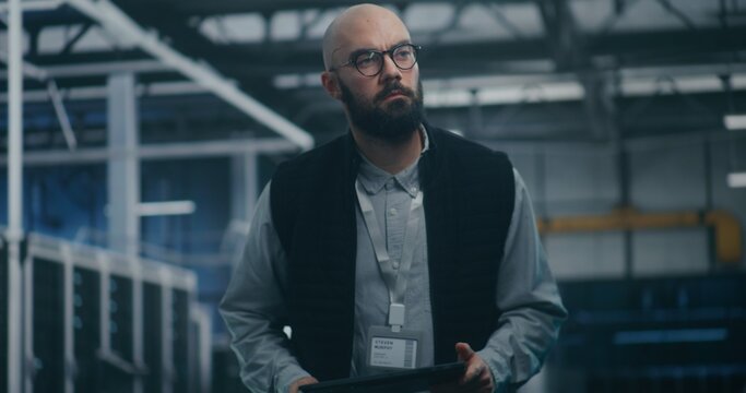 Specialist Checking Metrics on Personal Device. Data Management Specialist Checks Performance Metrics on Tablet While Surrounded by Vast Data Storage. Big Data, Server Performance, and Analysis. - Powered by Adobe