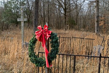 Red Christmas Wreath Hanging on Fence in Abandoned Cemetery