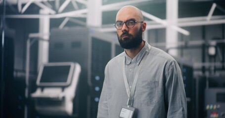 IT Professional Inspecting Rows of Active Server Racks. Male Engineer Walks Large Data Center, Conducting Physical Inspection of Glowing Server Racks. Security Protocol, Infrastructure Surveillance.