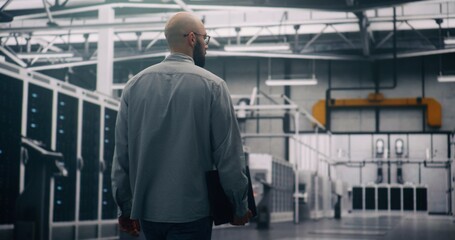 Professional Inspecting IT Infrastructure. Bearded Engineer Walks Between Rows of Servers, Seemingly Conducting Silent Technical Audit of Cloud Architecture. Technical Control and System Integrity.
