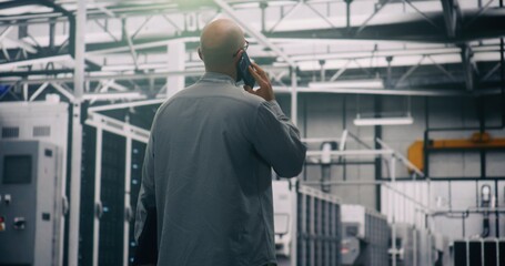 IT Specialist Makes Critical Call Troubleshooting Network Issues in Data Center. IT Engineer Talks on Phone While Walking Through Server Racks. Resolving Critical Network or Cloud Issues. Back View.