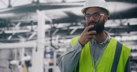 Factory Foreman Using Radio For Urgent Communication. Man in Safety Helmet Using Walkie Talkie For Urgent Communication on Noisy Production Floor. Concept Clear Communication and Site Supervision.