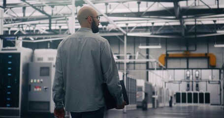Professional Inspecting IT Infrastructure. Bearded Engineer Walks Between Rows of Servers, Seemingly Conducting Silent Technical Audit of Cloud Architecture. Technical Control and System Integrity.