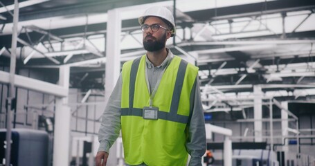 Engineer in Safety Vest Inspecting Production. Male Industrial Supervisor in Hard Hat Focused Inspecting Operations on IT Factory Floor. Industrial Safety, Production Management, Quality Control.