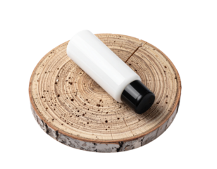 White cosmetic bottle with black cap on a wooden slice.