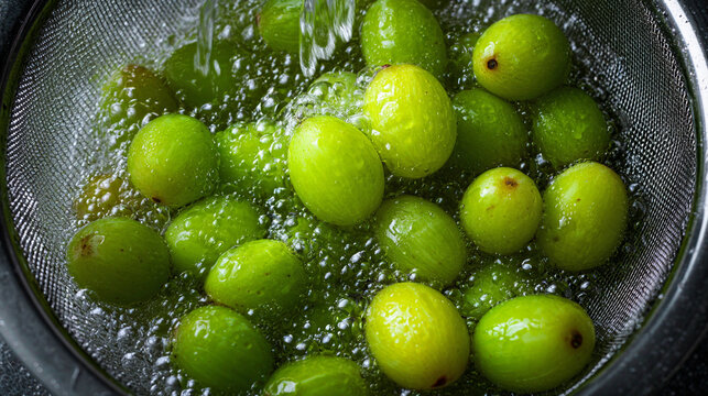 Fresh green gooseberries being rinsed in a metal colander, ready for cooking or eating - Powered by Adobe