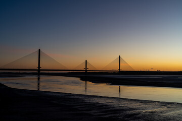 Obraz premium Mersey Gateway Bridge spanning the River Mersey at sunrise with exposed mudflats at low tide