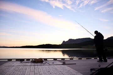 silhouette of a man fishing on fjord